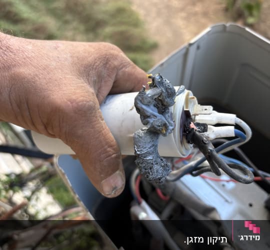 קבל מנוע שרוף ומותך שהוצא מיחידה חיצונית של מזגן בעת תיקון